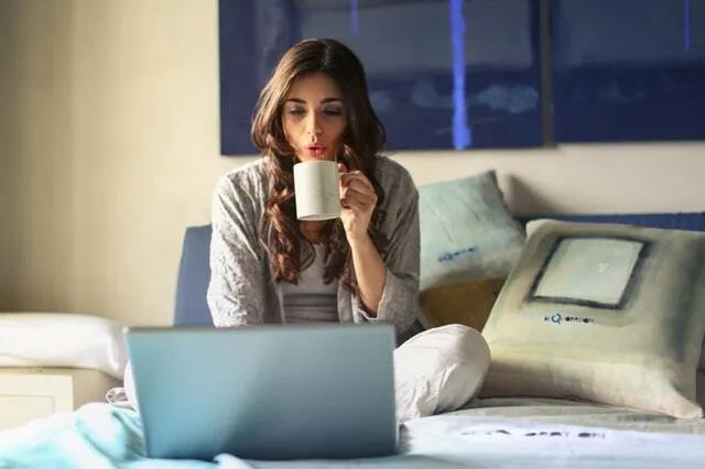 Woman sitting on bed working on a computer